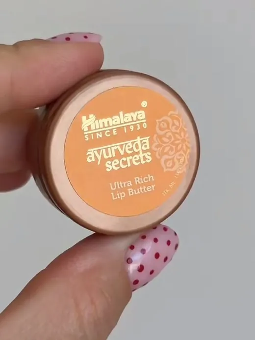 A creator holding a Himalaya lip butter to camera